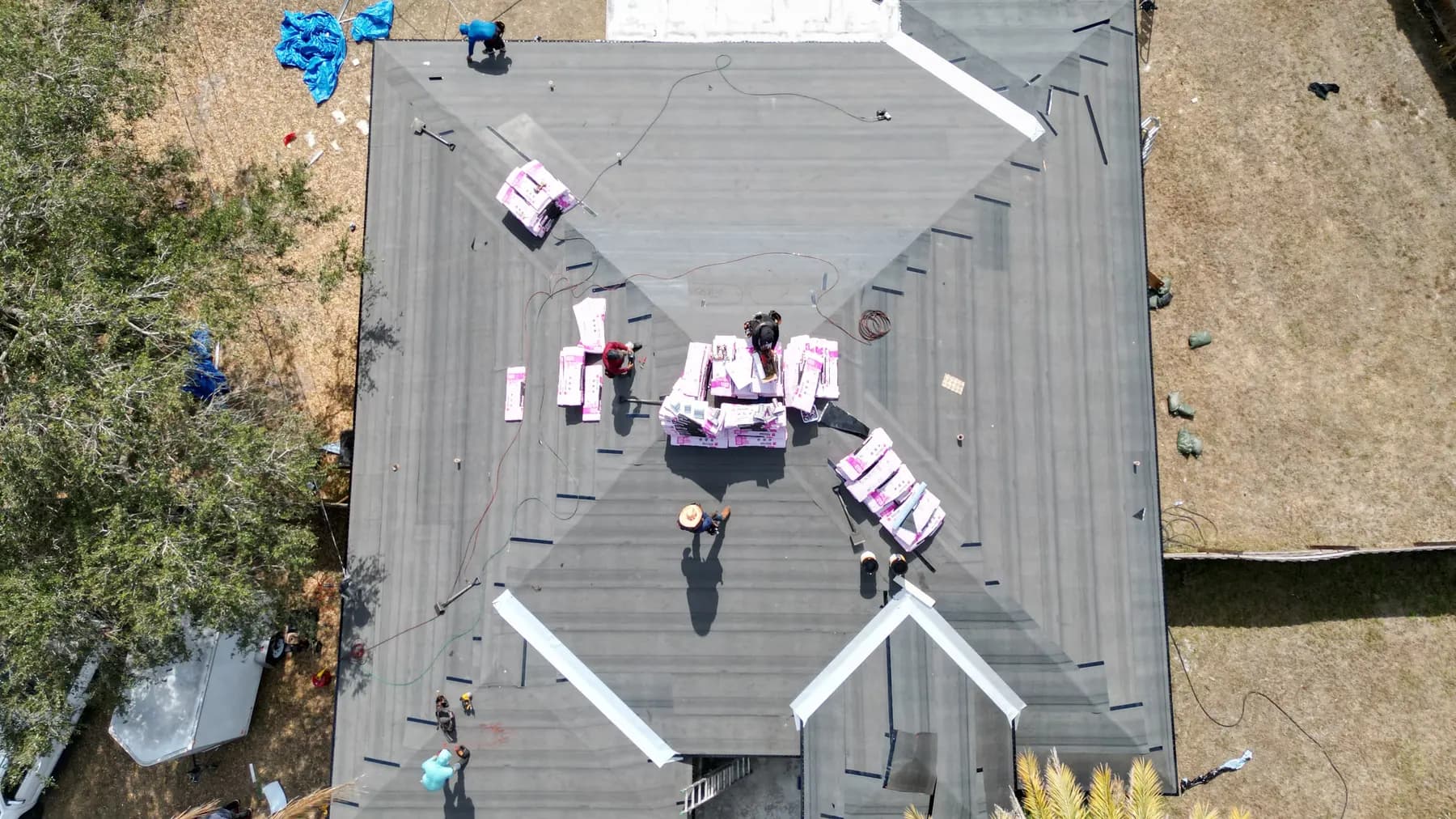 Crew on deck with staged pink Owens Corning shingle bundles over new underlayment